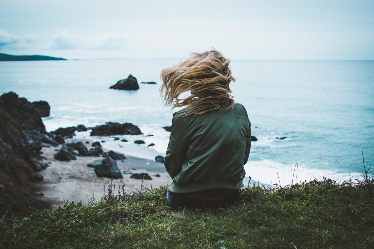 femme cheveux au vent et face à la mer