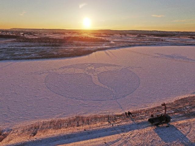 Il dessine un dragon géant dans la neige